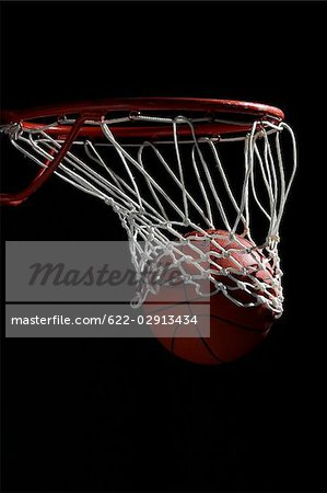 Basketball going through hoop against black background
