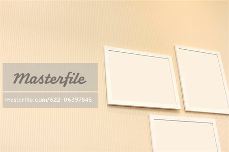 Three white frames hanging on a wall