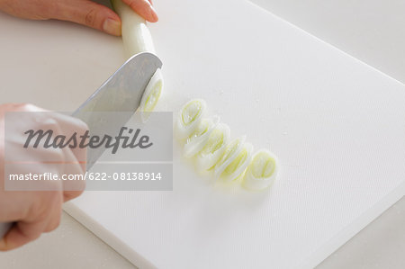 Close up of woman's hands slicing onions with a kitchen knife