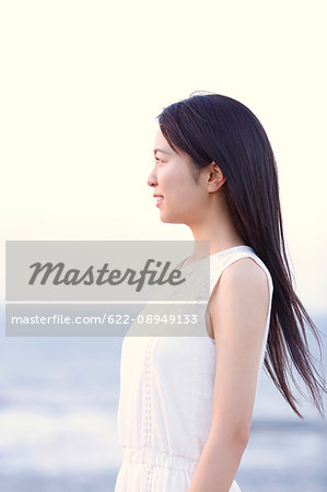 Young Japanese woman in a white dress at a cliff over the sea at sunrise, Chiba, Japan