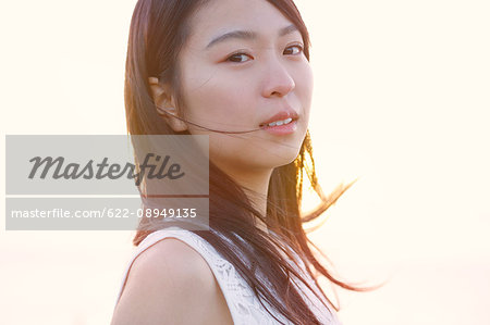 Young Japanese woman in a white dress at a cliff over the sea at sunrise, Chiba, Japan