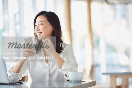 Japanese woman with smartphone in a stylish cafe