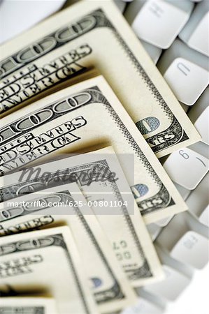 United States one hundred dollar bills on top of computer keyboard close-up