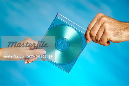 Close-up of a man and a woman's hands holding a compact disk