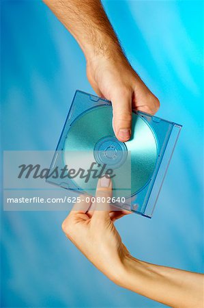 Close-up of a man and a woman's hands holding a compact disk