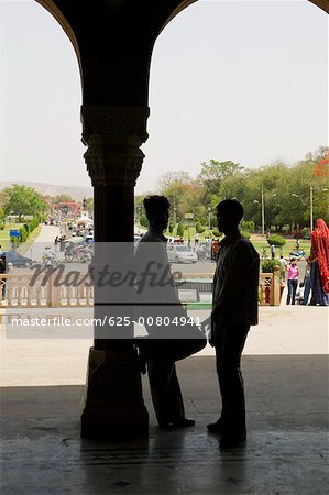 Two people standing against a column