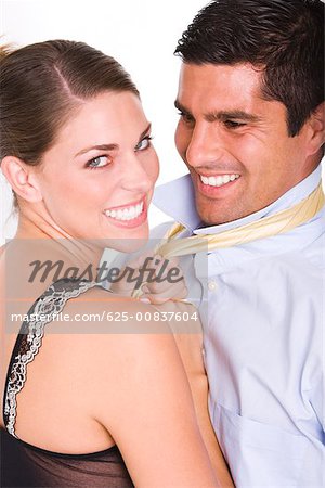 Side profile of a young woman pulling a mid adult man's tie