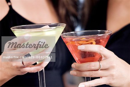 Mid section view of two young women toasting martinis