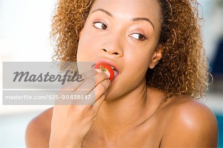 Close-up of a young woman eating a strawberry