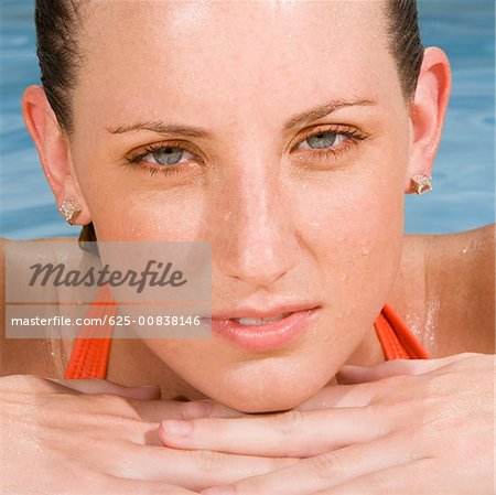 Portrait of a young woman leaning at the edge of a swimming pool