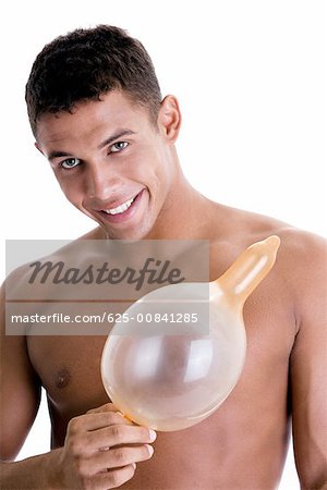 Portrait of a young man holding a blown condom