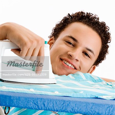 Portrait of a young man ironing his shirt