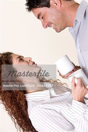 Side profile of a young woman and a mid adult man holding coffee cups