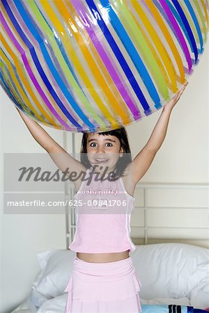 Close-up of a girl holding a large inflatable ball over her head