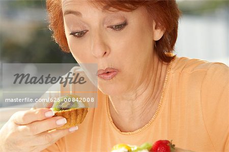 Close-up of a senior woman eating a fruit tart