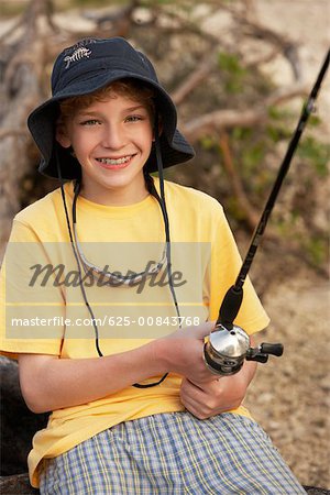 Close-up of a teenage boy holding a fishing rod - Stock Photo