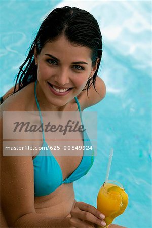 High angle view of a young woman holding a drink in a swimming pool