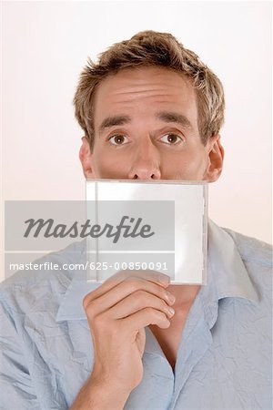 Portrait of a mid adult man holding a CD case in front of his mouth