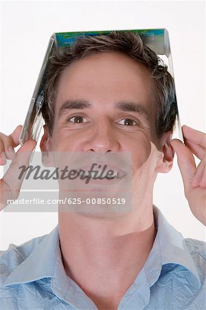 Portrait of a mid adult man holding a CD case on his head