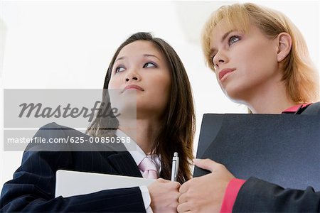 Low angle view of two businesswomen holding a laptop and a file