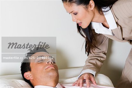 Businesswoman bending over a businessman sitting on a couch