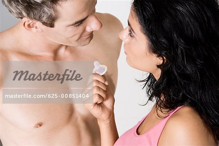 High angle view of a young woman showing a condom to a mid adult man