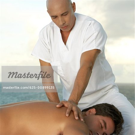 Close-up of a mature man giving a mid adult man a back massage