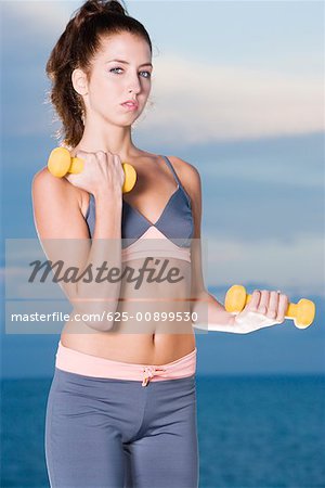 Portrait of a young woman exercising with dumbbells