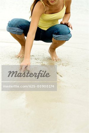 Girl writing in sand with her finger