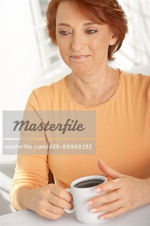 Close-up of a senior woman holding a cup of black coffee