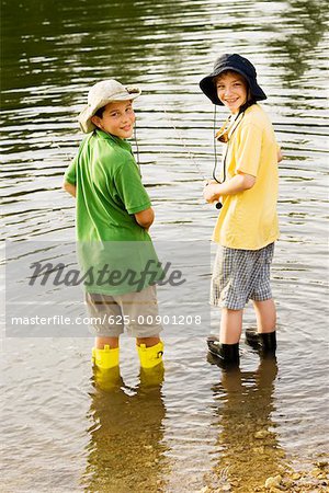 Rear view of two brothers fishing near a lake