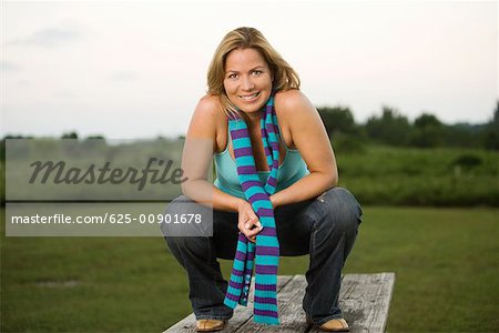 Portrait of a mature woman crouching on a picnic table