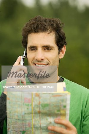 Portrait of a mid adult man talking on a mobile phone holding a map