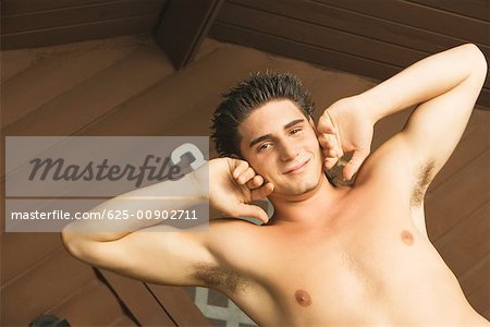 Portrait of a bare chested young man touching his cheeks smiling