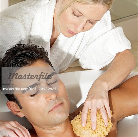 Message therapist rubbing a bath sponge on a young man's body