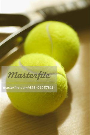 Close-up of two tennis balls with a tennis racket