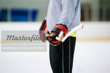 Mid section view of an ice hockey player holding an ice hockey stick
