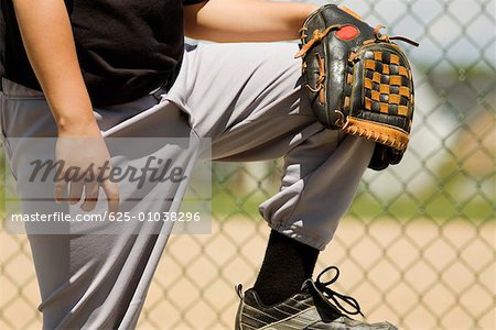 Mid section view of a baseball player holding a baseball glove
