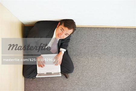 High angle view of a businessman sitting on the floor and using a laptop