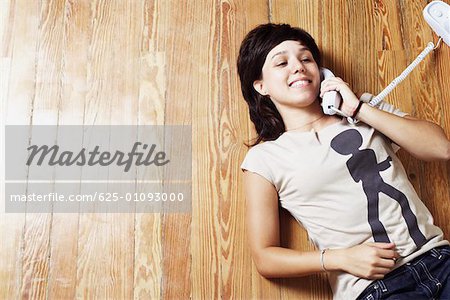 High angle view of a young woman lying on the floor and talking on the telephone