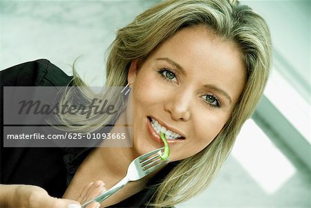 Portrait of a mid adult woman eating a slice of fruit