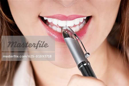 Close-up of a businesswoman smiling with a pen on her lips