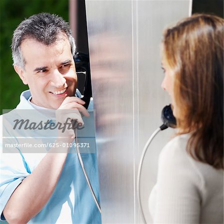 Close-up of a mid adult couple talking on a pay phone