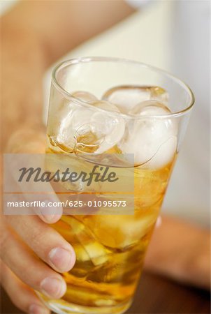 Close-up of a human hand holding a glass of whiskey