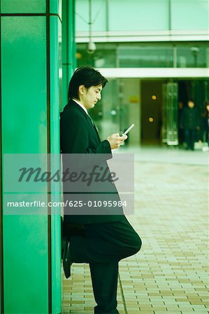 Side profile of a mid adult man operating a mobile phone