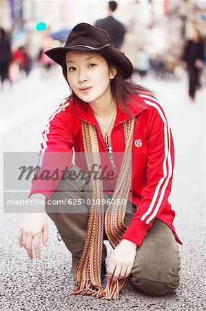 Portrait of a young woman squatting on the street