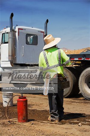 Rear view of a construction worker standing in front of a cement truck