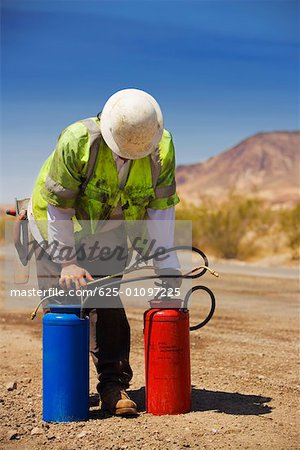 Construction worker holding two cylinders