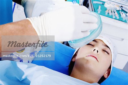 Surgeon's hand putting an oxygen mask on a female patient