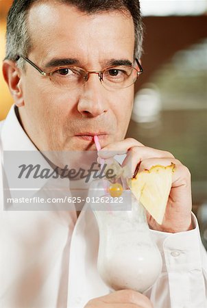 Portrait of a mid adult man drinking pina colada with a drinking straw